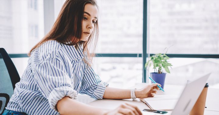 Woman working on computer and writing in a notebook