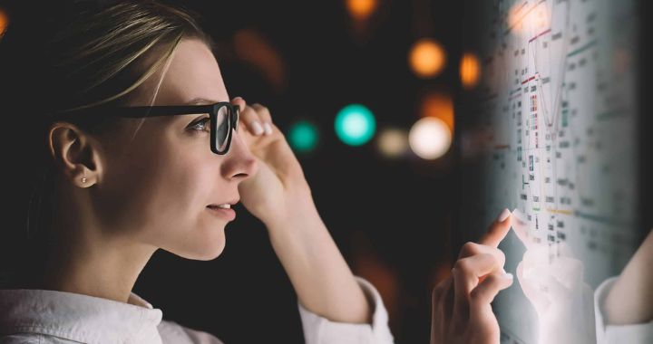 Woman touching her glasses and looking at a board