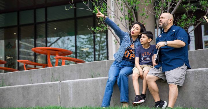 Woman pointing off in the distance while sitting next to her young son and husband